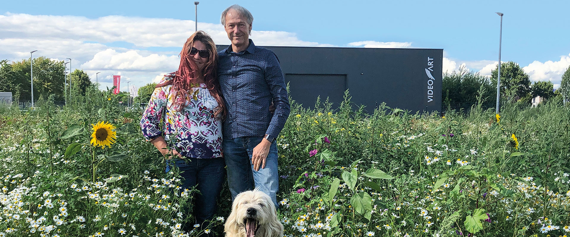 Marion und Michael Gillner mit Hund in der Blumenwiese am Firmengelände